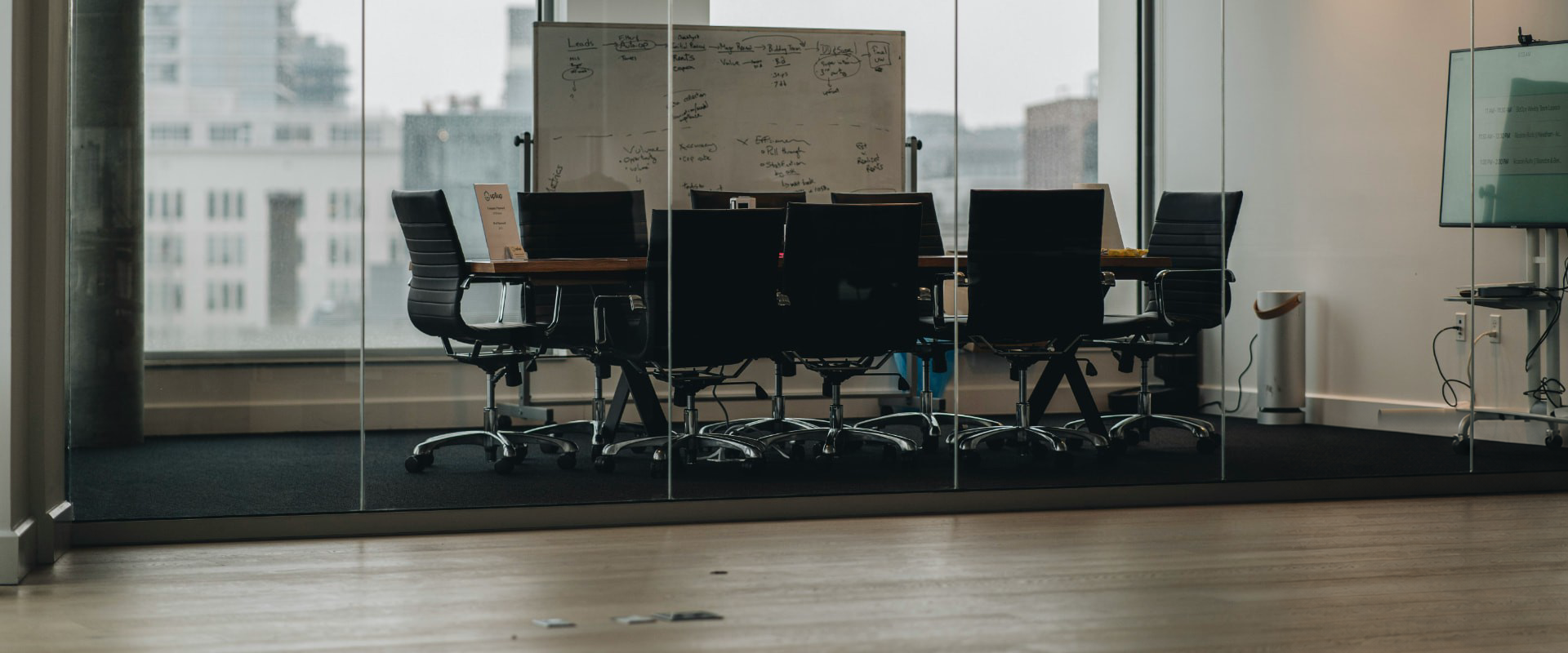 Empty conference room with a wooden meeting table, chairs and a whiteboard covered in diagrams