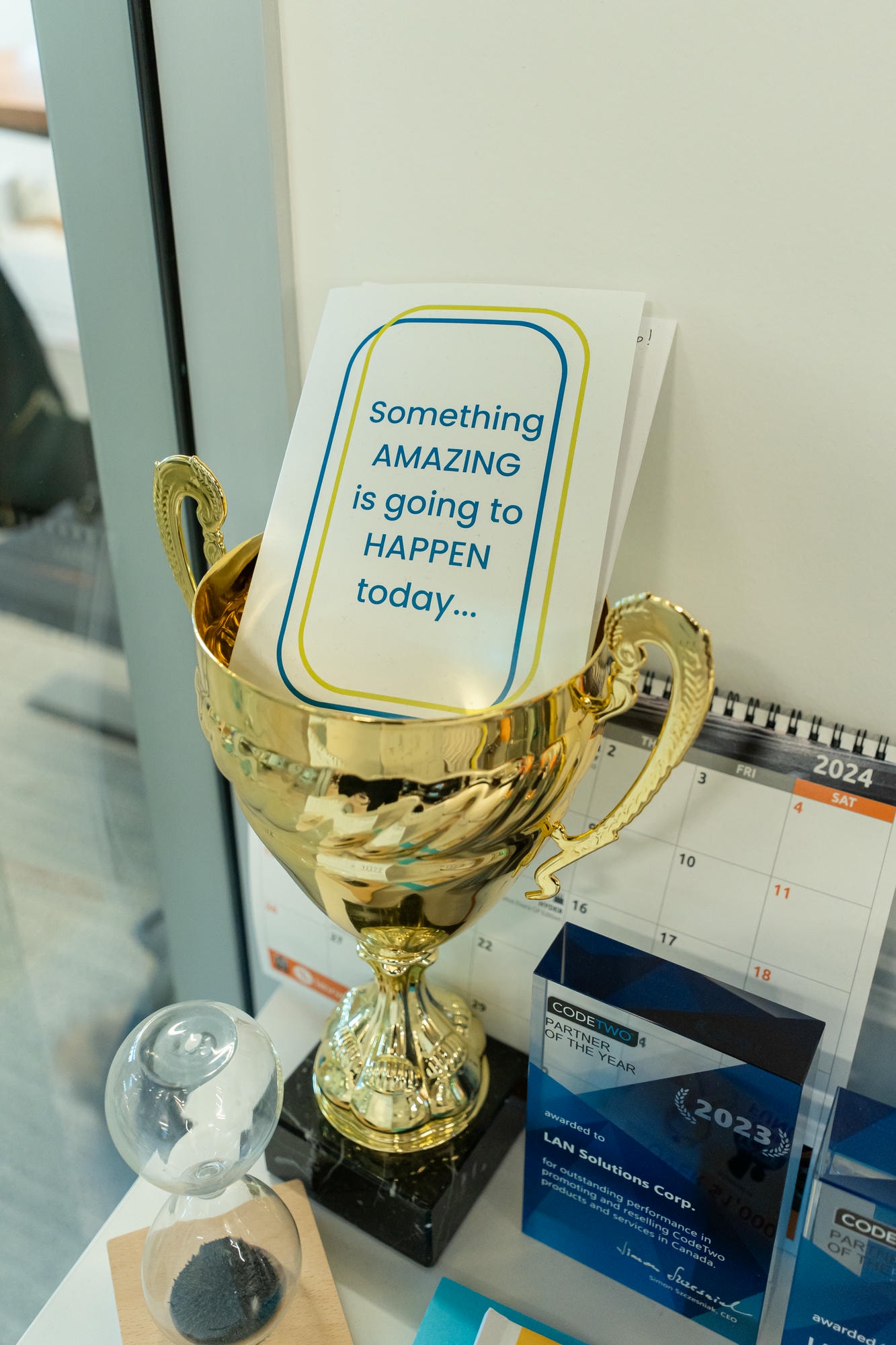Close-up of a golden trophy holding a card that reads ‘Something amazing is going to happen today,’ symbolizing optimism and achievement in business
