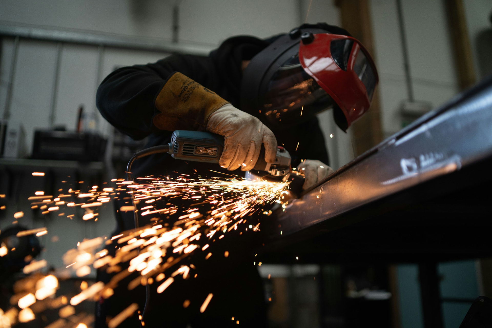 Fabricator using an angle grinder on a steel beam, sparks flying