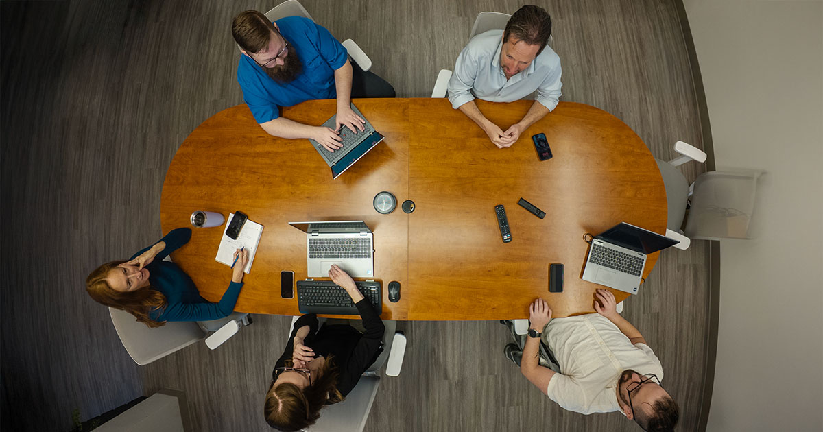 Group of IT professionals at LAN Solutions boardroom table, strategizing technology solutions for clients